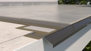 Detal krawędzi tarasu z płytkami ceramicznymi i profilem okapowym K100, pokazujący estetyczne wykończenie oraz ochronę krawędzi konstrukcji.