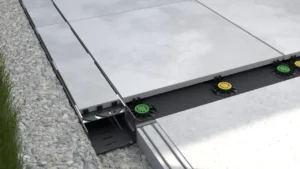 Krawędź tarasu wentylowanego z płytami tarasowymi na regulowanych wspornikach oraz rynną odwadniającą zapewniającą skuteczne odprowadzenie wody.