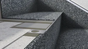 Zbliżenie na krawędź stopnia z posadzką żywiczną typu kamienny dywan, pokazujące profil schodowy i warstwy wykończeniowe konstrukcji.